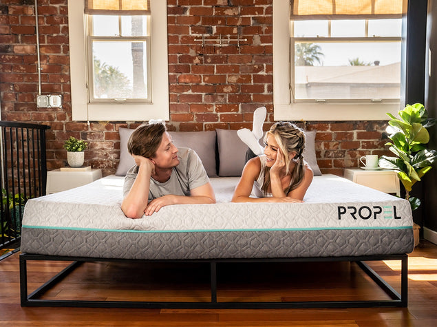 Couple laying at the feet of the Propel Dual-Sided All-Foam Mattress